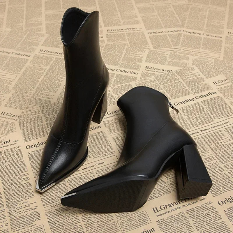 Close-up of stylish women's ankle boots featuring a distinctive shiny chrome toe tip design.