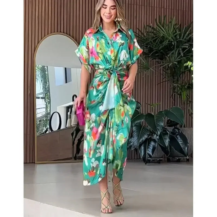 Woman gracefully posing in a flowing green floral button-down maxi dress. Elegant, chic, and perfect for summer.