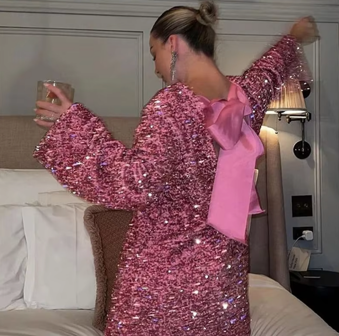 Shimmering sequin party dress, sleeveless, with eye-catching back bow. Perfect for festive evenings.