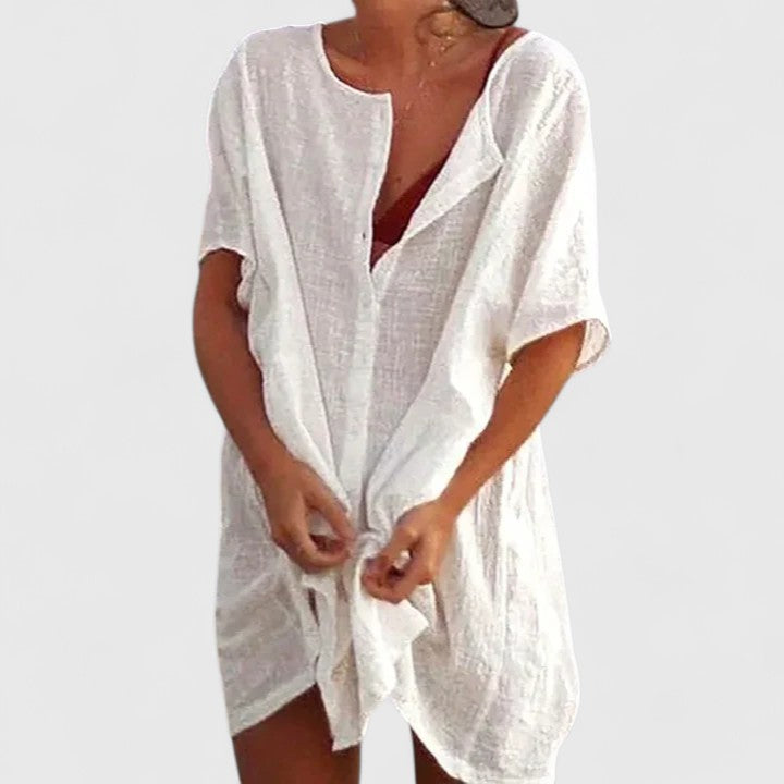 Women's elegant tunic dress accessorized with summer sandals and a hat, ready for a chic casual day. Fashionable.