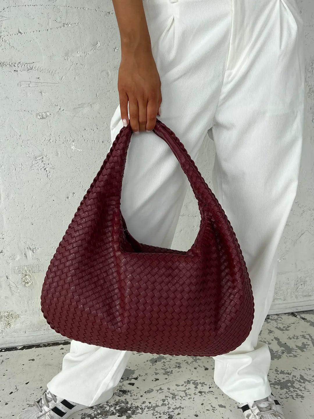 Front view of a women's woven shoulder bag, showcasing its elegant design and spacious interior.