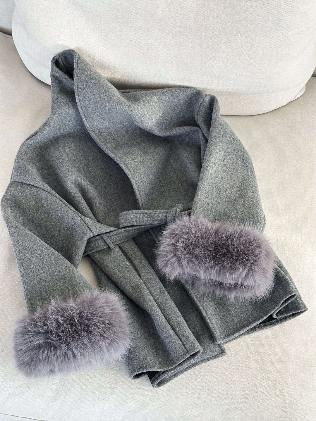 Women's elegant outerwear: a long belted wrap coat with luxurious faux fur details.