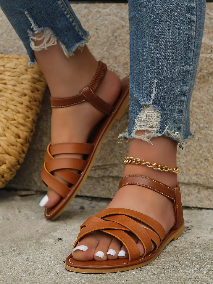 Stylish women's open-toe slip-on flat sandals with elegant cross straps, perfect for casual summer.
