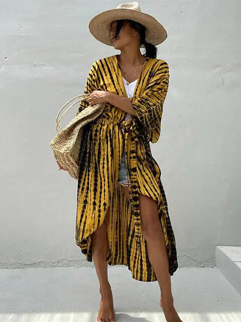 Woman modeling a flowy tie-dye sarong cover-up on a sunny beach.