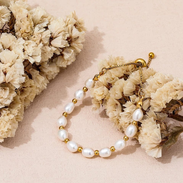 Hand wearing an elegant women's pearl and gold bracelet, a classic accessory suitable for gifting.