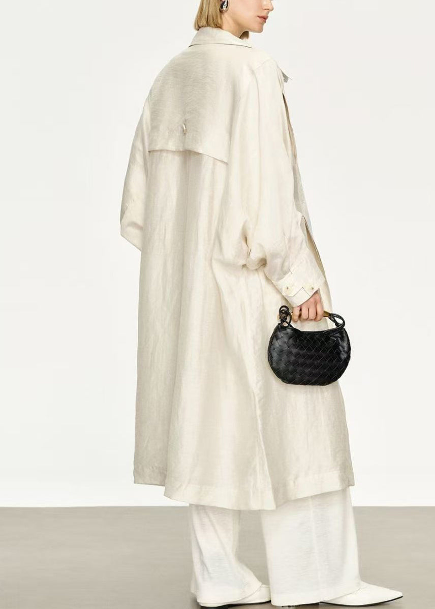 Flowing women's long trench coat; elegant Peter Pan collar & distinctive bat sleeves. Chic autumn outerwear.