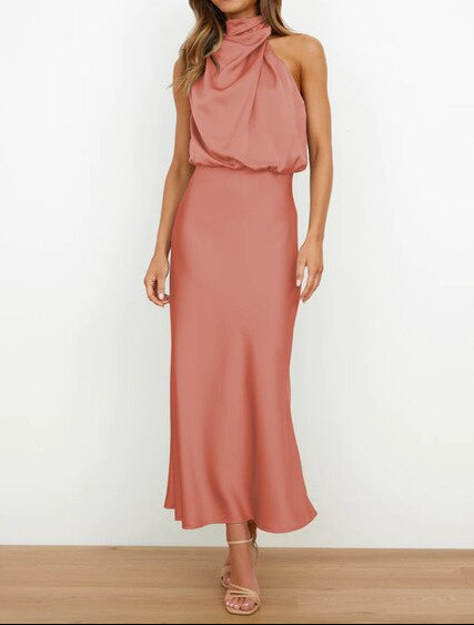 Sophisticated woman wearing an elegant long halter neck cocktail dress for a summer party.
