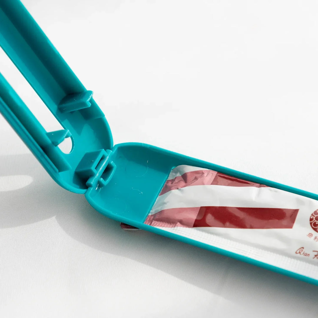 Hand holding a pet food dispenser spoon, demonstrating hygienic feeding and tube squeezing function.