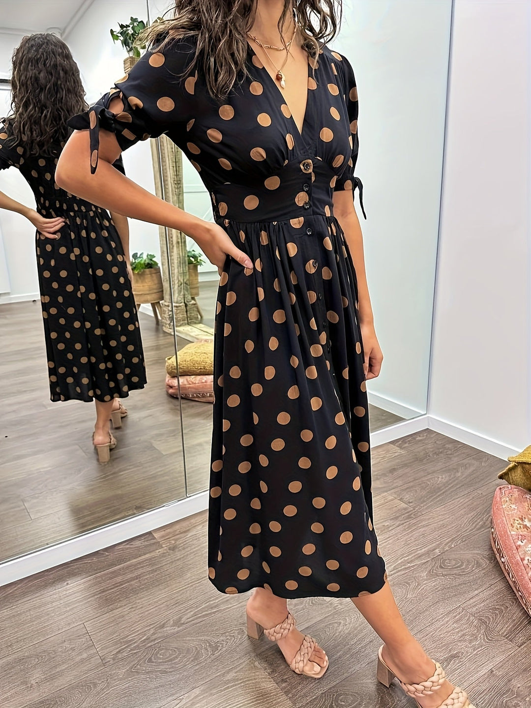 Fashionable women's polka dot midi dress. Black with white dots, v-neckline, and tie sleeve details for an elegant look.
