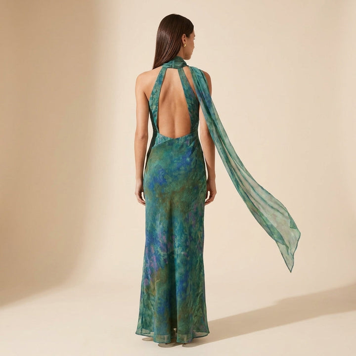 Fitted women's sleeveless maxi dress with a halter neck and open back, featuring an elegant artistic print.
