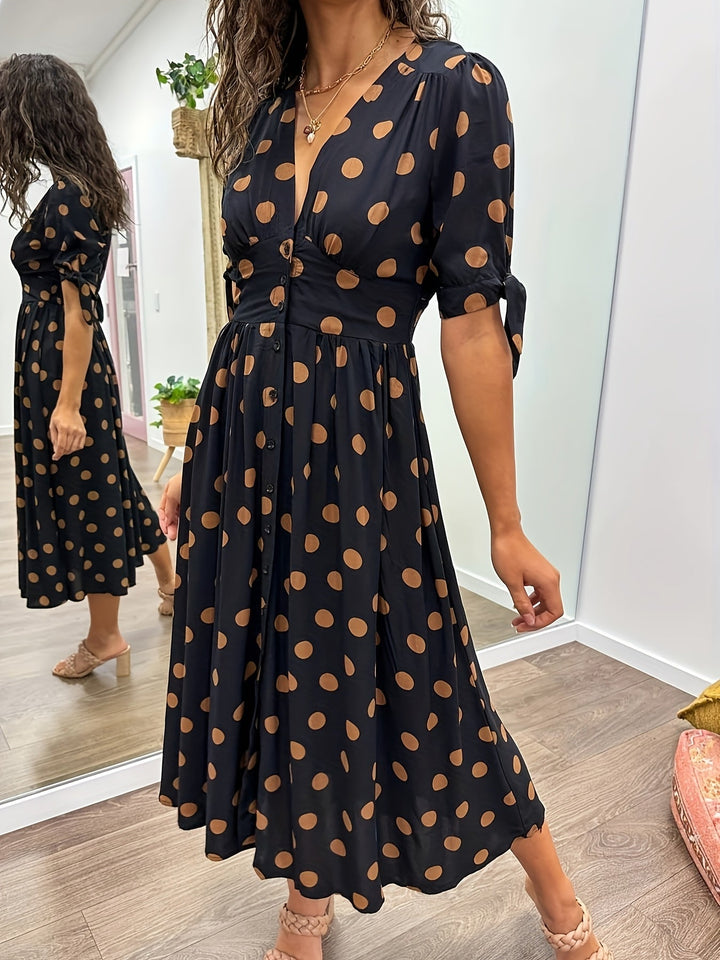 Stylish women's midi dress featuring a classic black polka dot pattern, flattering v-neck, and trendy tie sleeves.