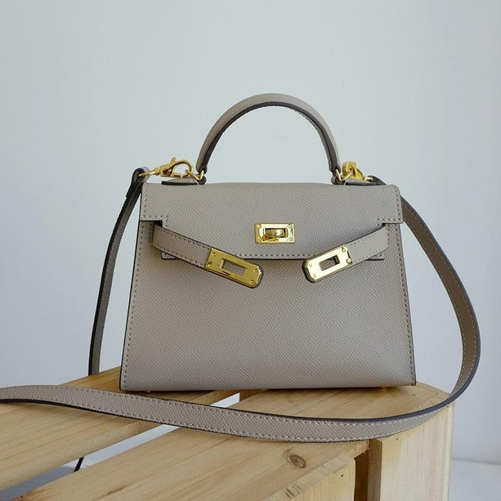 Chic creme structured top handle handbag for women, highlighting its sturdy form and luxurious gold lock.
