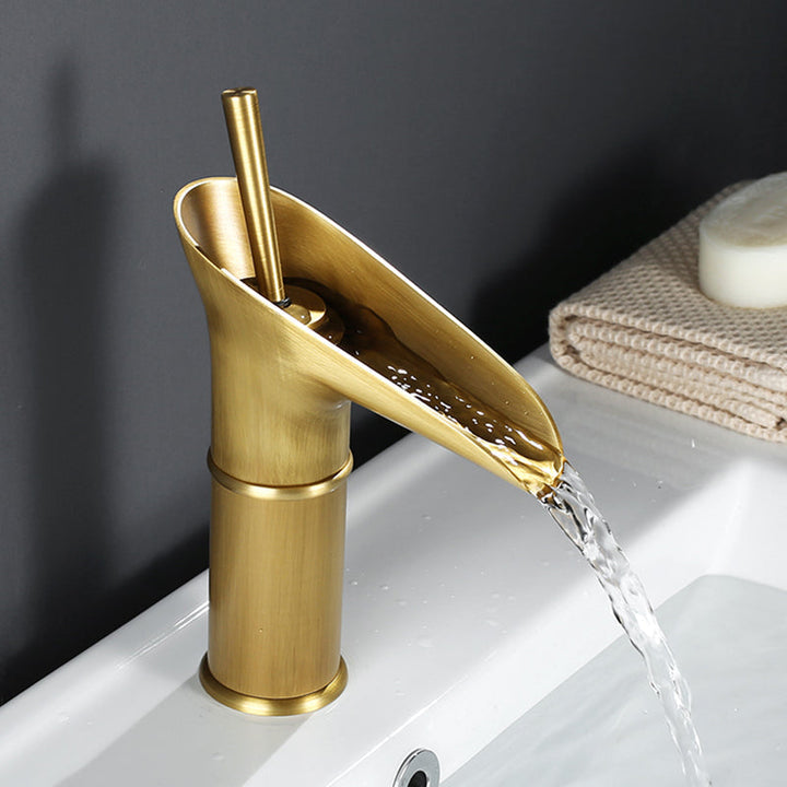 Polished brass waterfall faucet, sleek design for luxurious bathroom basins.