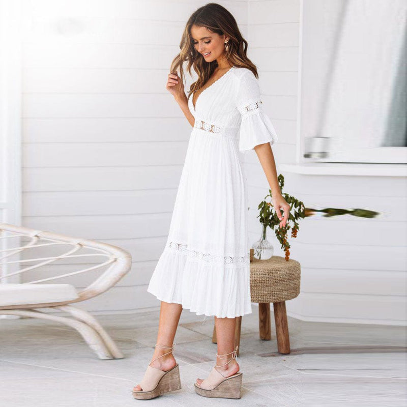 Flowy white V-neck midi dress with intricate lace trim & flutter sleeves. A chic women's beach dress for warm weather.