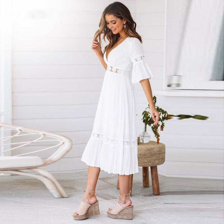 Flowy white V-neck midi dress with intricate lace trim & flutter sleeves. A chic women's beach dress for warm weather.