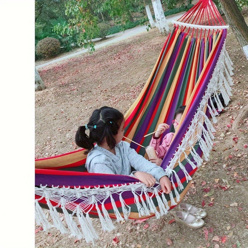 Relaxing double hammock, colorful stripes & bohemian tassels for patio decor.