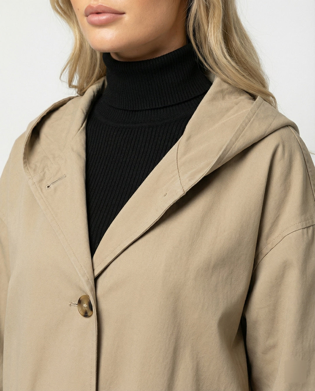 Close-up of durable, windproof & waterproof fabric on a women's long trench coat, ideal for rainy weather.