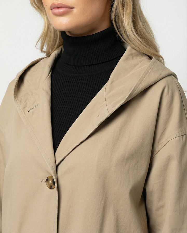 Close-up of durable, windproof & waterproof fabric on a women's long trench coat, ideal for rainy weather.