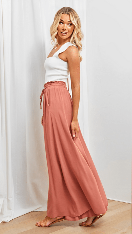 Woman relaxing in comfy & elegant Lily wide-leg trousers with elastic waist.