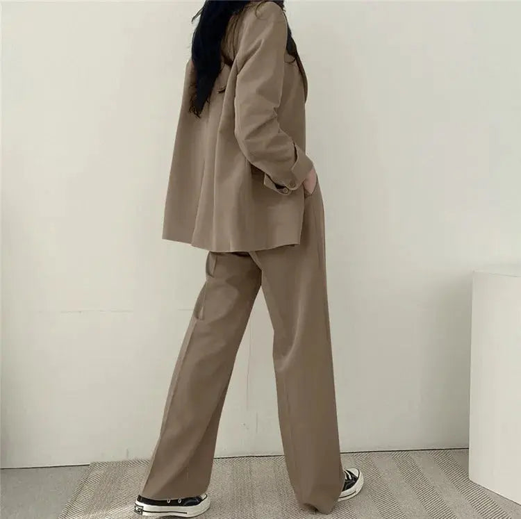 Model standing confidently in women's tailored blazer and matching trousers.