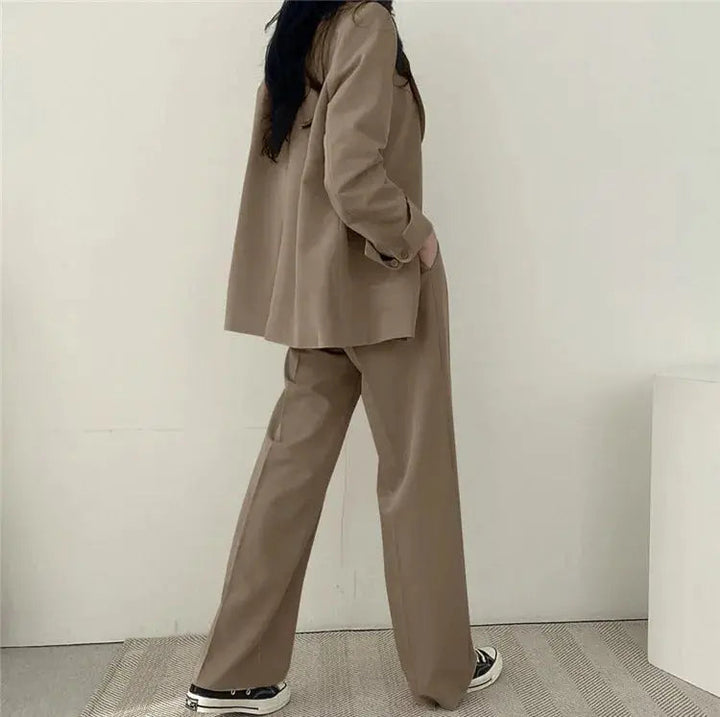 Model standing confidently in women's tailored blazer and matching trousers.