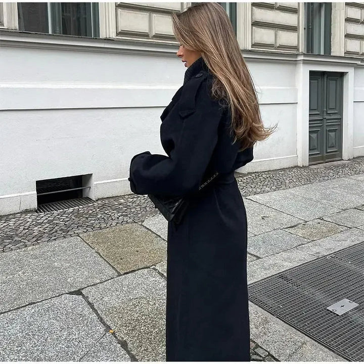 Sophisticated black women's trench coat. Double-breasted style, a long design with a classic belted waist for outerwear.