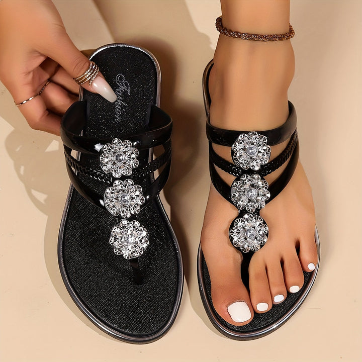 Close-up of dazzling rhinestone details on women's T-strap flat summer sandals.