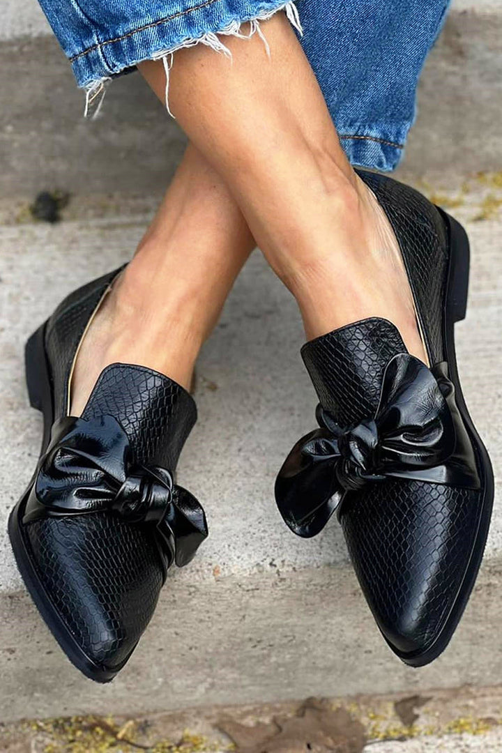 Elegant black women's slip-on loafers featuring a delicate bow detail, ideal for chic everyday and dressy outfits.