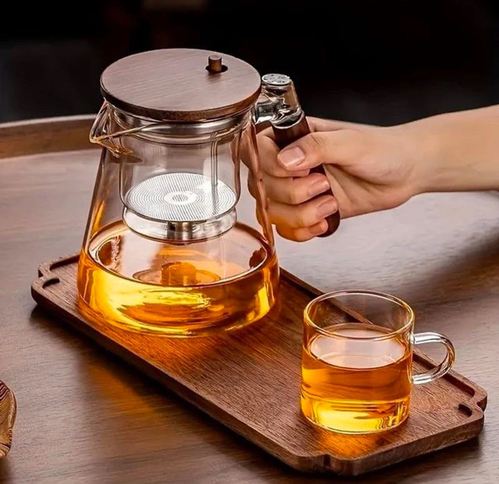 Clear glass teapot with fine mesh tea infuser & stylish wooden handle. Borosilicate, heat-resistant, for tea brewing.