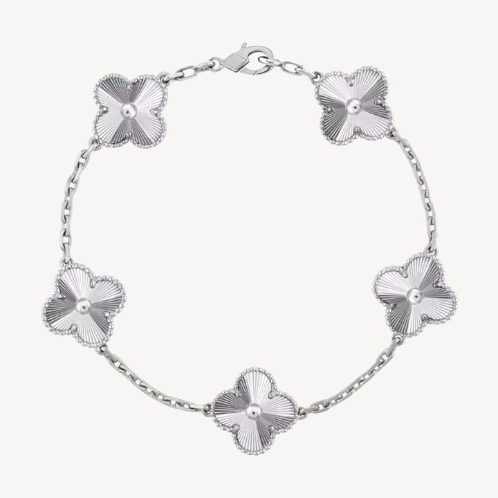Elegant clover charm bracelet with polished black agate inlays and a gold and silver-tone chain for sophisticated style.