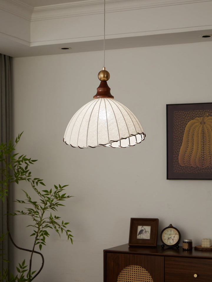 Elegant pendant light with pleated fabric shade, gold-finished top, and wood accent; perfect for modern interiors.