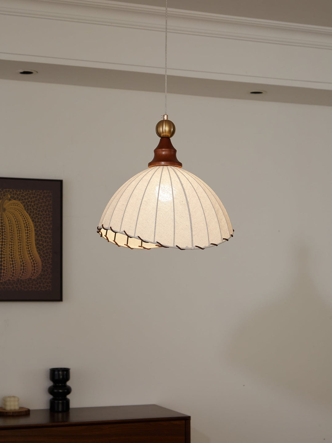 Elegant pendant light with pleated fabric shade, gold-finished top, and wood accent; perfect for modern interiors.