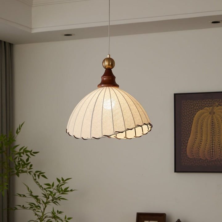 Elegant pendant light with pleated fabric shade, gold-finished top, and wood accent; perfect for modern interiors.