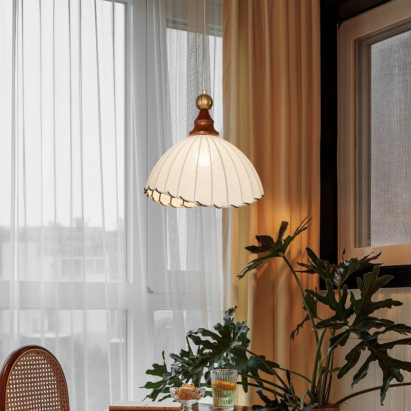 Elegant pendant light with pleated fabric shade, gold-finished top, and wood accent; perfect for modern interiors.