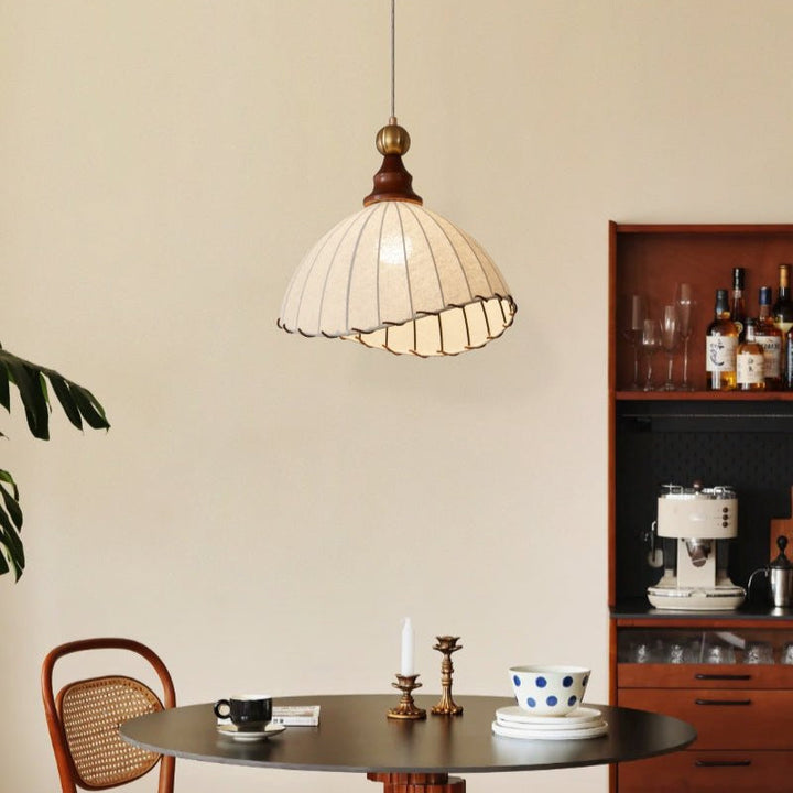 Elegant pendant light with pleated fabric shade, gold-finished top, and wood accent; perfect for modern interiors.
