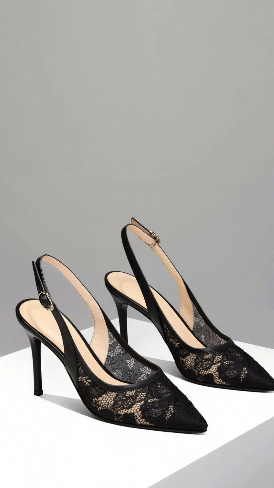 Close-up of elegant women's lace-patterned slingback heels with a sharp pointed toe, formal footwear.