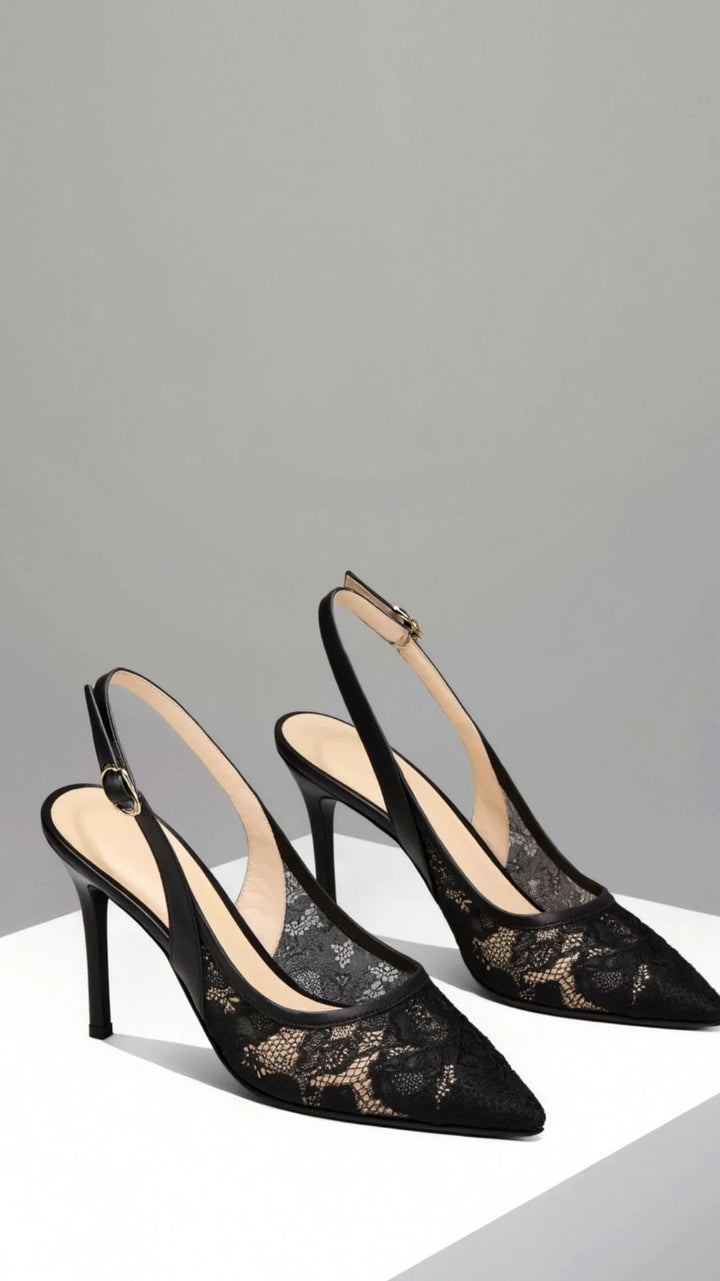 Close-up of elegant women's lace-patterned slingback heels with a sharp pointed toe, formal footwear.