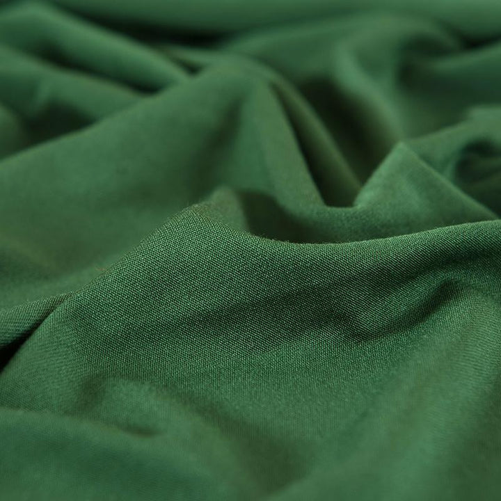 "Emerald green sofa cover on a couch, showcasing its stretchy and durable fabric, perfect for protection and style."