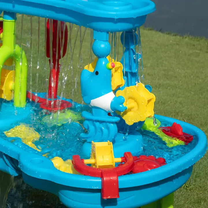 Vibrant plastic children's water table set up in a lush green garden, perfect for summer outdoor play.
