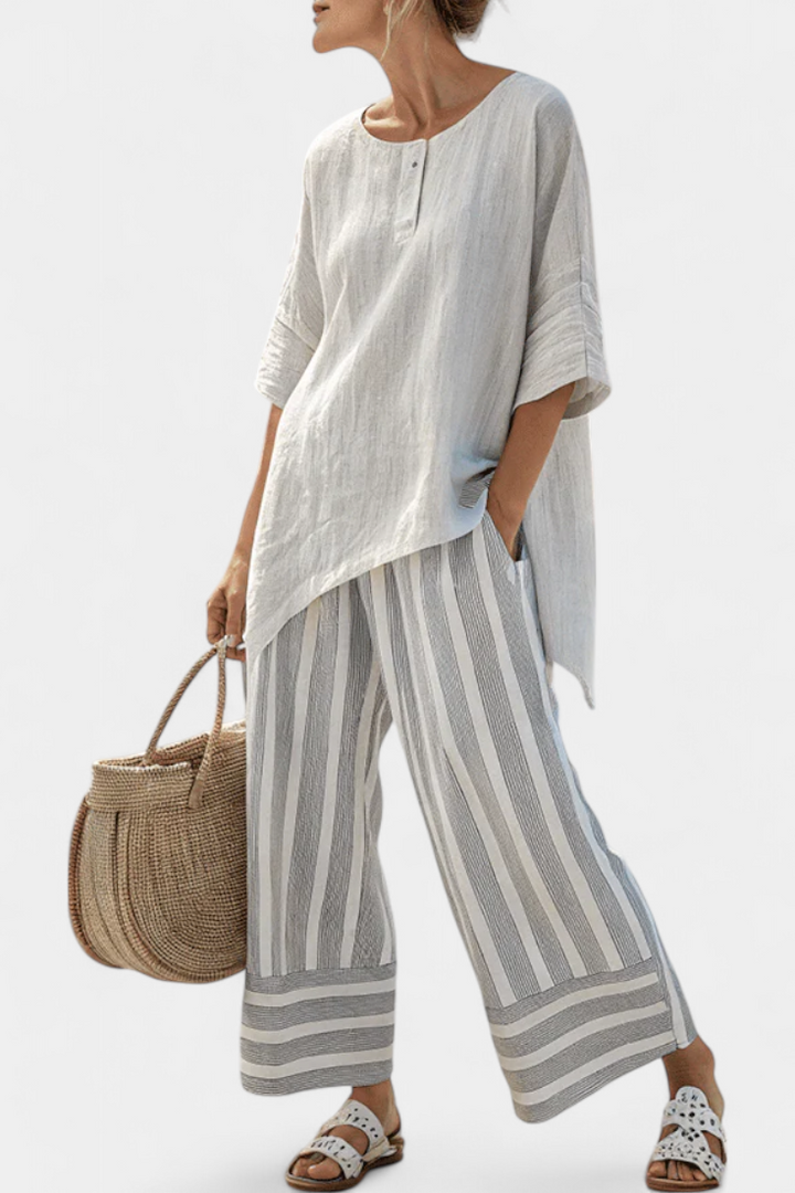 Elegant women's two-piece set: flowy asymmetrical blouse & multi-colored striped wide-leg pants. Perfect for summer.