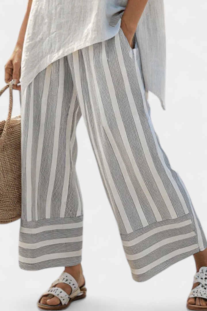 Stylish women's asymmetrical blouse & multi-colored striped wide-leg pants set. Elegant casual two-piece outfit.