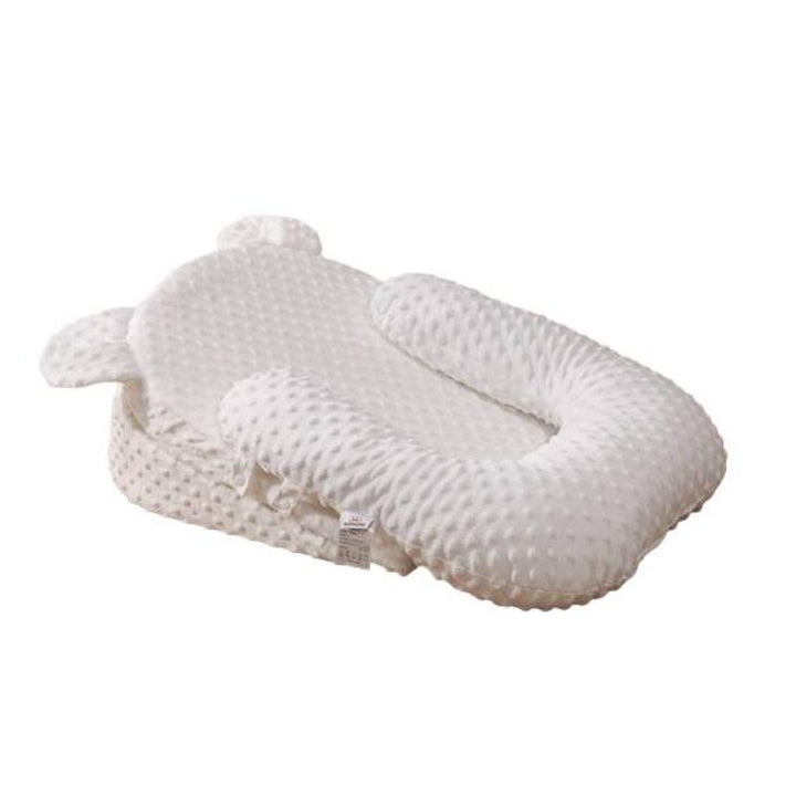 Happy baby feeding on a supportive anti-reflux newborn pillow, preventing spit-up & aiding digestion for comfort.