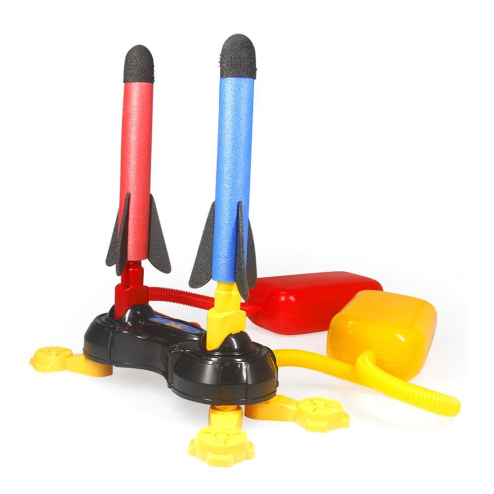 Kids launching foam rockets high with an air-powered rocket launcher toy set outdoors. Fun STEM active play.