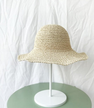 Stylish women's straw bucket hat with a wide brim, offering excellent sun protection for beach days.
