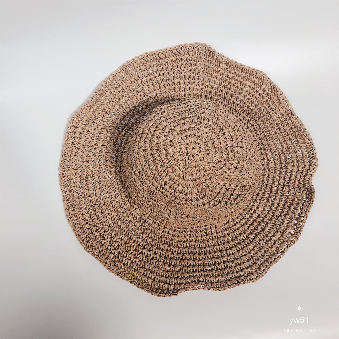 Elegant women's wide brim straw bucket hat, perfect beachwear for summer sun protection.