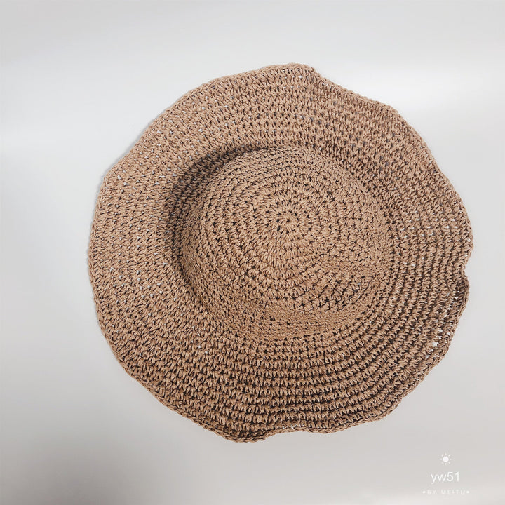 Elegant women's wide brim straw bucket hat, perfect beachwear for summer sun protection.