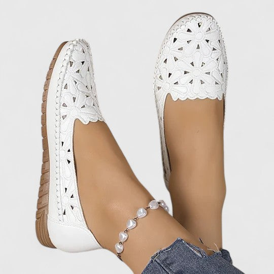 White perforated slip-on flat shoes for women, versatile and breathable casual wear.