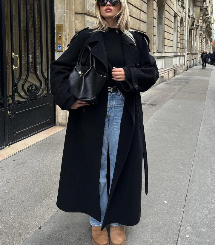 Close-up of a chic black women's double-breasted trench coat, highlighting the classic style and belted waist. Fall fashion.