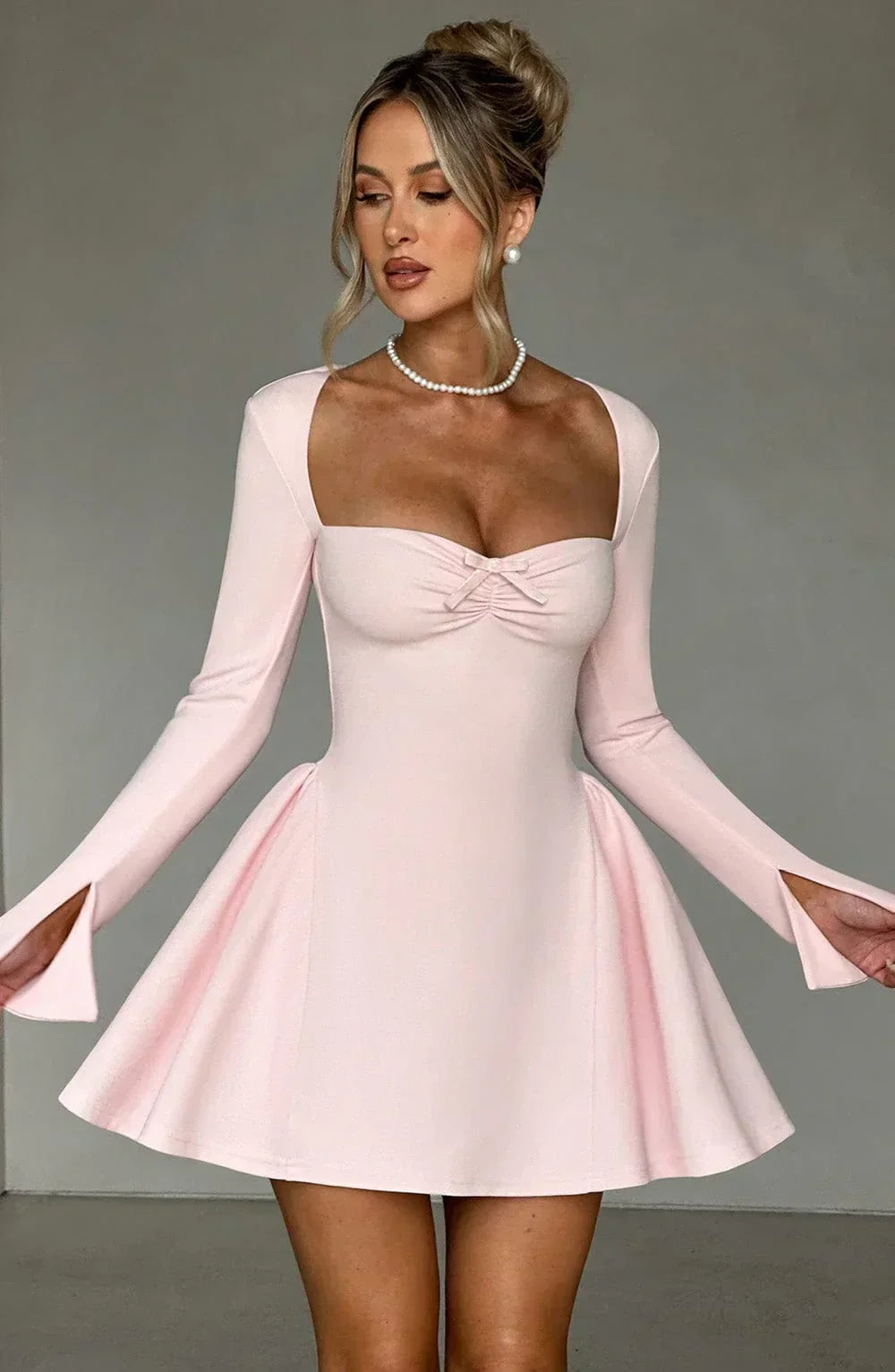 Front view of sophisticated women's pleated A-line long sleeve mini dress. Autumn party essential.