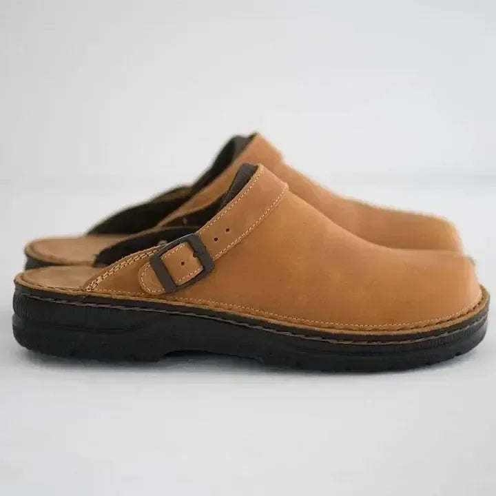 Man wearing comfortable men's casual slip-on clog mules with adjustable buckle. Everyday lounge footwear.